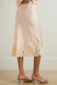 Detail of pink satin pajama skirt with elegant lace trim hem and sleek silk finish.