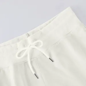 Detail of lightweight white high-waist pants featuring elastic ribbing and drawstring.