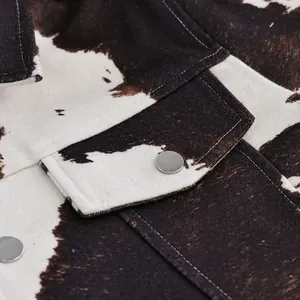 Detailopname van het korte jasje met koeprint en zilveren drukknopen en zachte textuur
