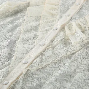 Detailansicht der zarten floralen Spitzenstruktur und des Rüschendesigns der Bluse