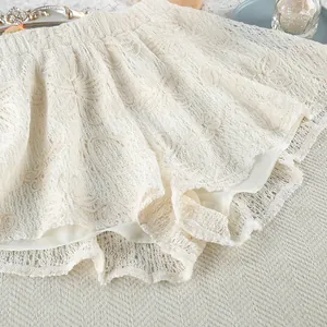 Vista dettagliata dei pantaloncini in pizzo floreale bianco crema con ricamo all'uncinetto.
