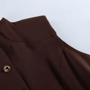 Close-up of a brown retro dress showing high neck detail and a decorative gold button.