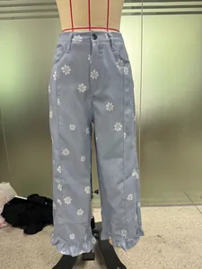 Light blue wide-leg denim pants featuring white daisy floral print and stylish ruffled hems