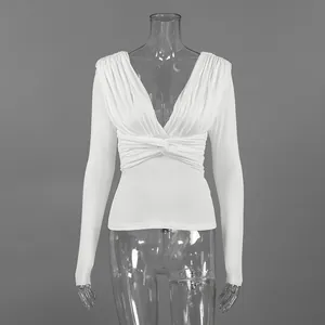 Detalle de blusa de modal blanca con cuello en V y drapeado en la cintura sobre maniquí.