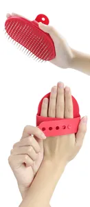 Detailed view of red pet grooming brush with stainless steel needles and adjustable hand strap