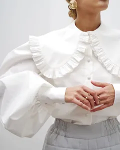 Detail of white cotton shirt featuring ruffled Peter Pan collar and puff sleeves.