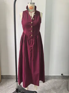 Detail van een bordeaux mouwloze maxi-jurk met reverskraag en gouden knoopaccenten.