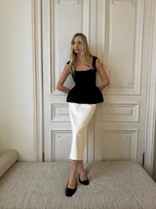 Haut à basque noir de style français élégant associé à une jupe midi blanche