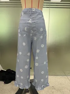 Back view of light blue Y2K wide-leg denim pants featuring white daisy prints and ruffles