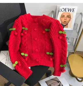Detailed view of a red chunky knit cardigan featuring 3D cherry accents and round buttons.