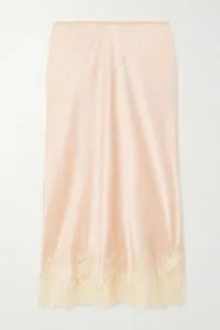 Detail view of satin midi skirt showing elegant lace trim hem on peach fabric