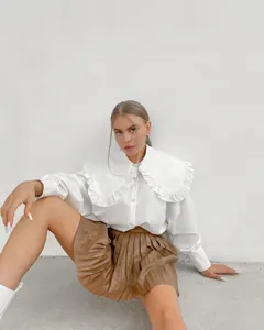 Detailed view of a French style white shirt with an oversized ruffled doll collar
