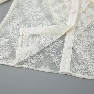 Nahaufnahme eines weißen Jacquard-Spitzenhemds mit zarten Blumenmustern und Knöpfen