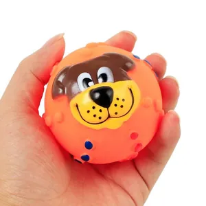 Close-up of orange squeaky dog ball toy with cute cartoon face held in hand