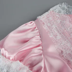 Close-up of pink satin dress with delicate white lace trim and puff sleeve details
