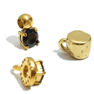 Détail macro de breloques en acier inoxydable doré 18K avec des pierres noires taillées.