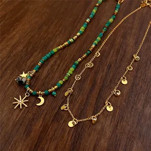 Primo piano di una collana bohémien vintage con ciondoli a luna e sole su sfondo legno.