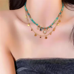 Primo piano di una collana bohémien vintage con perline turchesi, pendenti luna e stella.