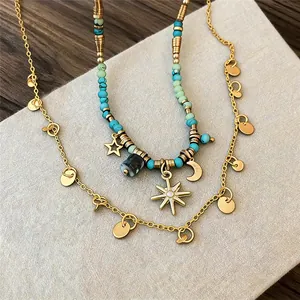 Dettaglio di una collana boho con perline turchesi e ciondoli celestiali color oro