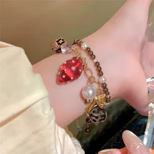 Vue détaillée d'un charmant bracelet en perles avec pendentif fraise et joli nœud