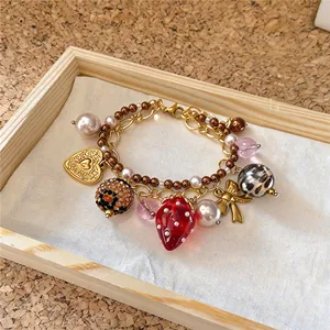 Détail d'un bracelet à breloques fraise avec perles et pendentif cœur doré