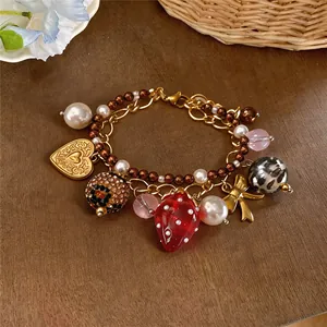 Gros plan détaillé d'un bracelet doux avec pendentif fraise, perles et breloques dorées