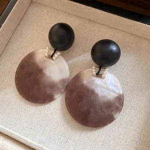 Dettaglio di eleganti orecchini rotondi in legno e acrilico marmorizzato in una scatola