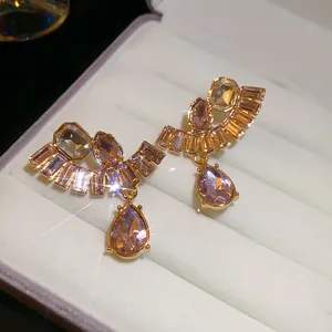 Detailansicht französischer Ohrringe mit goldenem Finish und rosa Kristallanhängern.