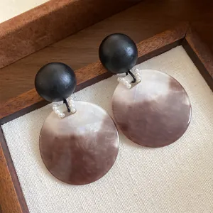Dettaglio orecchini stile francese con sfera di legno e disco in acrilico marmorizzato