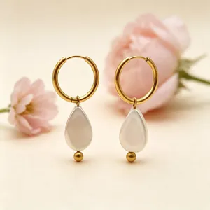 Gros plan sur de magnifiques boucles d'oreilles perles gouttes dorées chic.
