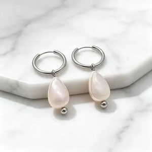 Gros plan détaillé de boucles d'oreilles françaises en nacre sur marbre blanc