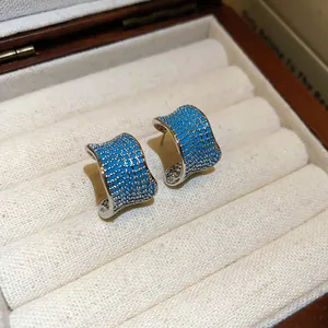 Primo piano di orecchini vintage a forma di C con vivaci pietre di zircone blu pavé
