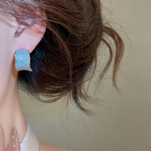 Primo piano di eleganti orecchini a forma di C con pietre di zircone blu sul modello