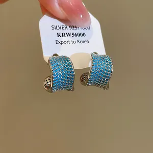 Primo piano di orecchini vintage a forma di C placcati in oro 18k con zirconi blu.