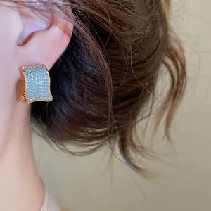Primo piano di orecchini a forma di C placcati in oro 18k con zirconi blu pavé