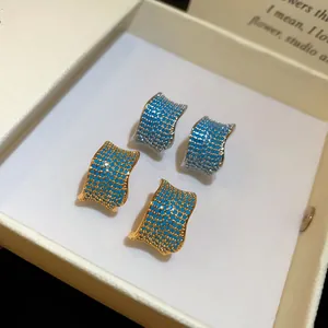 Primo piano di orecchini vintage a forma di C con pietre blu in scatola