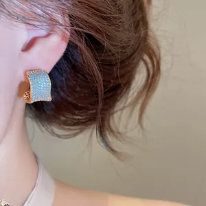 Dettaglio di orecchini vintage a forma di C con zirconi blu e placcatura in oro 18 carati