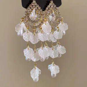 Primer plano de pendientes vintage con cristales, pétalos blancos y perlas colgantes