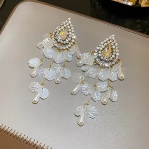 Primer plano de elegantes pendientes de borla con perlas, conchas y brillantes