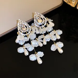 Vista detallada de pendientes de plata con diamantes de imitación, perlas y pétalos.
