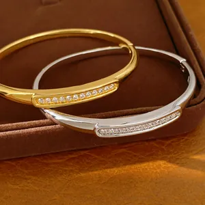 Close-up of gold and silver 18K gold-plated oval bangles featuring zircon stone inlay