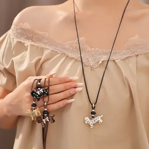 Close-up of puppy pendant necklaces with polka dots and bows worn by a female model.