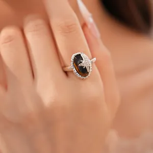Exquisiter Vintage-Ring mit ovalem Tigerauge und Zirkon-Stern am Finger des Modells