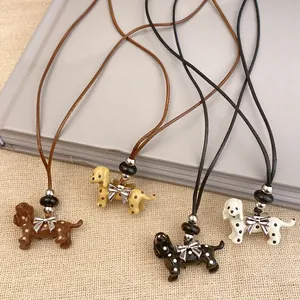 Close-up of four dog-shaped pendants with polka dots and bow accents on leather cords.