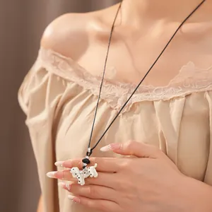 Detailed macro shot of white polka dot puppy pendant necklace on black leather cord