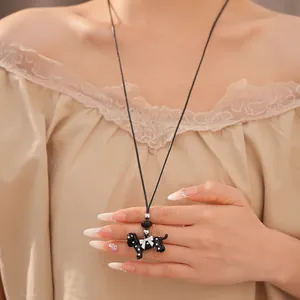 Close-up detail of a cute black polka dot dog pendant necklace on a leather cord.