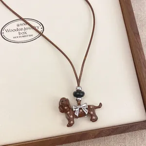Macro view of a brown enamel dachshund dog necklace pendant with a silver bow detail