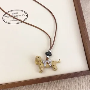 Close-up of a spotted puppy pendant necklace with a bow on a leather cord display