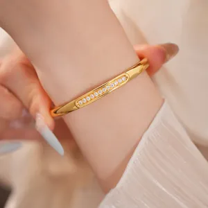 Close-up detail of 18K gold-plated oval bangle with shimmering cubic zirconia stone inlay