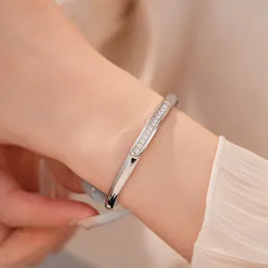 Close-up of silver-plated oval bangle with pave-set sparkling cubic zirconia on wrist.
